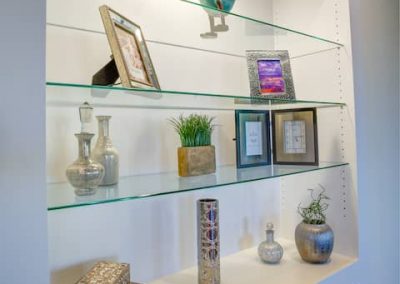 A shelf with glass shelves and some decorative items.
