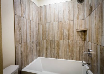 A bathroom with wood tile and white fixtures.
