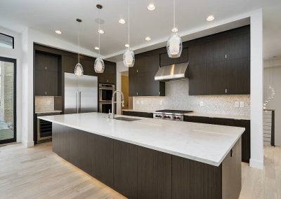A kitchen with white counters and dark cabinets.