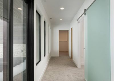 A hallway with a sliding glass door and white walls.