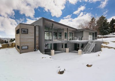 A large modern house with snow on the ground.