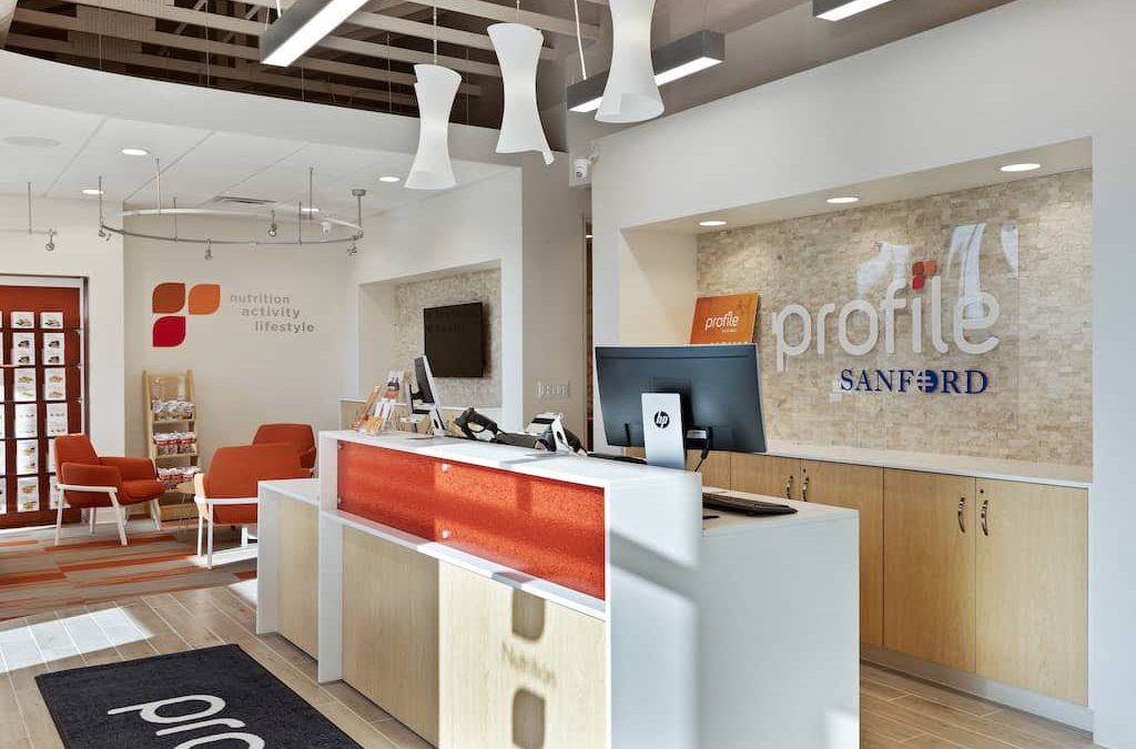 A reception desk with orange chairs and white walls.