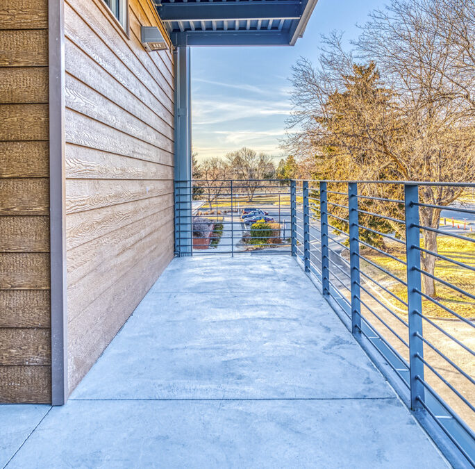 A balcony with blue metal railing and wood siding.