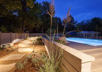 A pool area with grass and rocks at night.