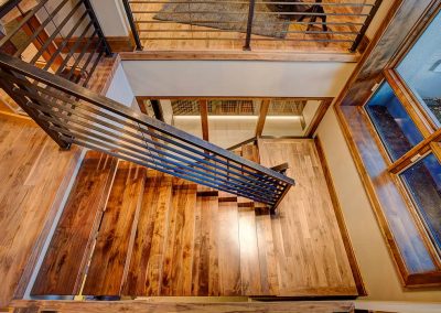 A wooden staircase with metal railing and wood floors.