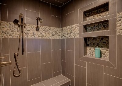 A tiled shower with a bench and shelves.