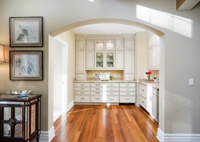 A kitchen with white cabinets and wood floors