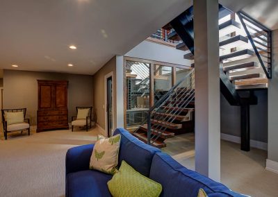 A couch in the middle of a room with stairs.