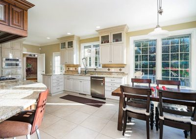 A kitchen with white cabinets and brown chairs