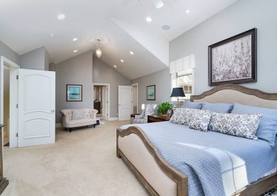 A large bedroom with a king size bed and vaulted ceiling.