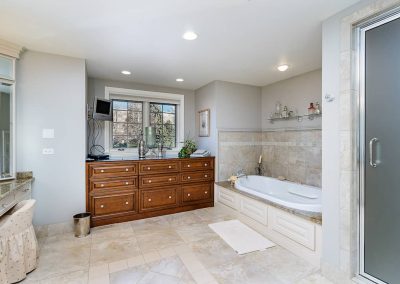 A bathroom with a large tub and wooden cabinet.