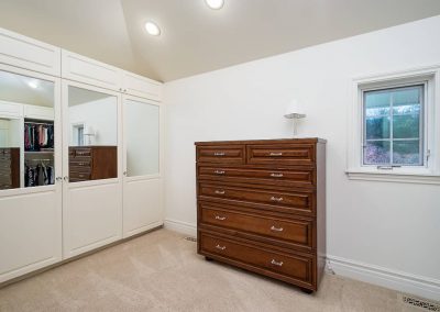 A bedroom with a dresser and mirror in it
