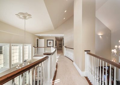 A large hallway with a wooden railing and white walls.