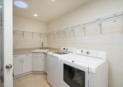 A white laundry room with two machines and sinks.