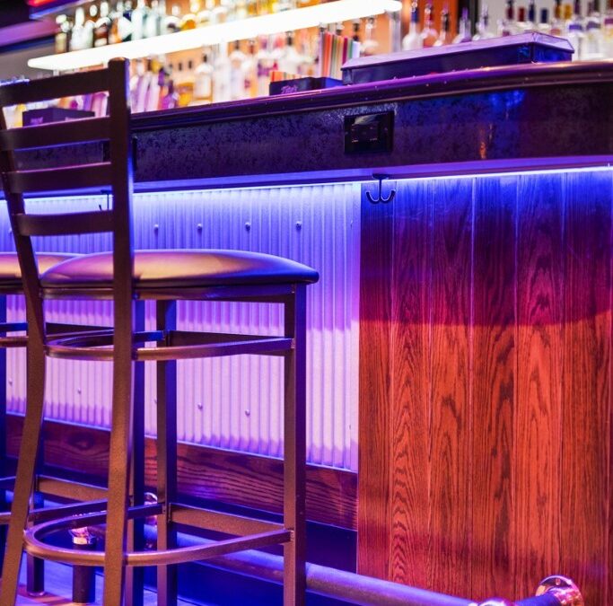 A bar with chairs and lights in the background
