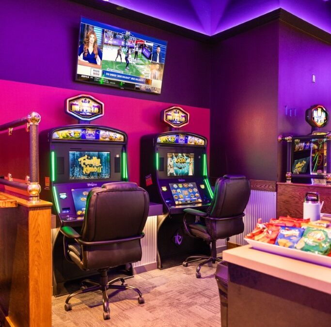 A room with two gaming machines and purple walls.